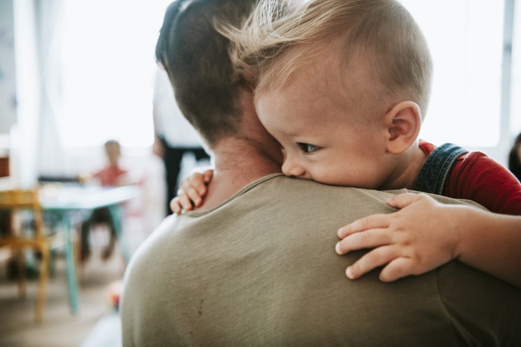 Father carrying his toddler son into a classroom