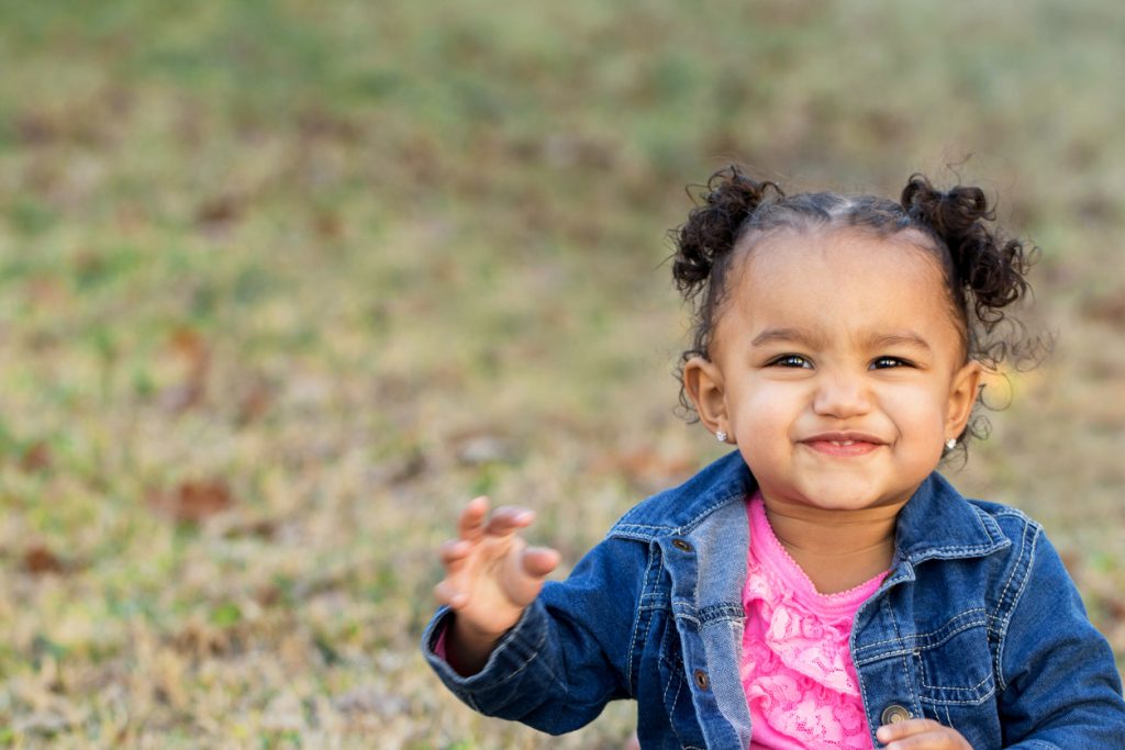 Toddler girl smiling outside