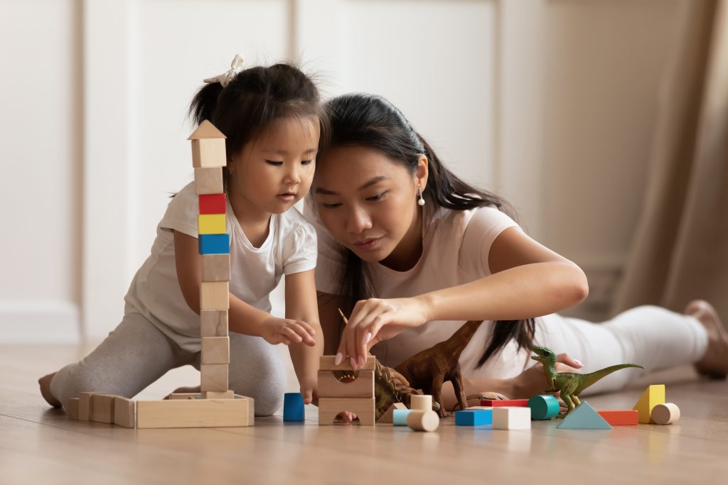 Mother and toddler playing with blocks on the floor.